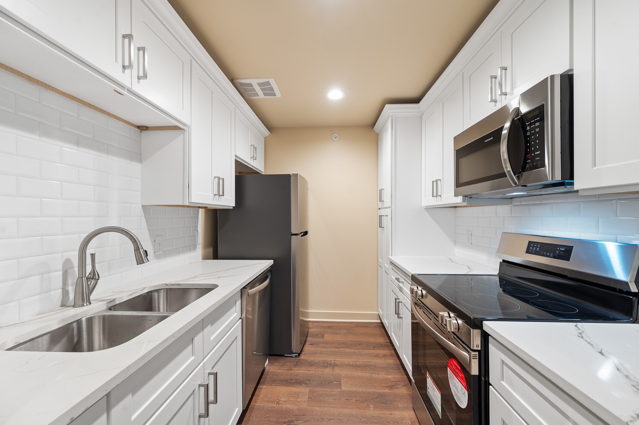 2829 Timmons Lane, Unit 201 Houston, TX 77027 - Photo 17 of 42 a kitchen with stainless steel appliances a sink a stove a microwave a sink a refrigerator and cabinets