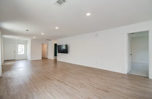 a view of an empty room with wooden floor and a window