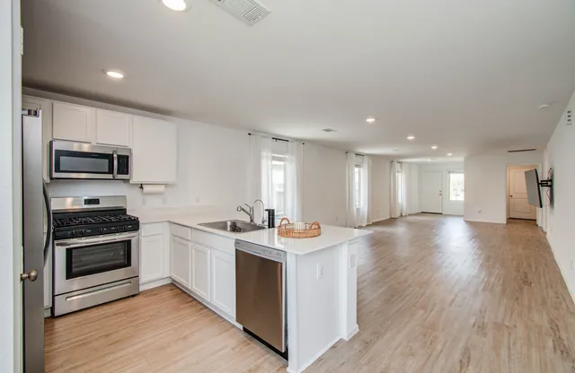 a kitchen with stainless steel appliances granite countertop a sink stove and wooden floor