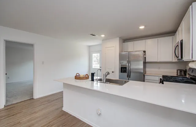 a kitchen with stainless steel appliances a sink a stove a refrigerator and cabinets