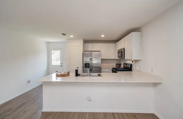 a kitchen with stainless steel appliances a sink a stove a refrigerator cabinets and a dining table