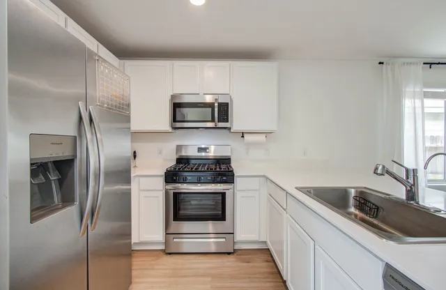 a kitchen with stainless steel appliances a stove a sink and a refrigerator