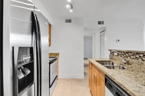 a kitchen with granite countertop a sink and a refrigerator
