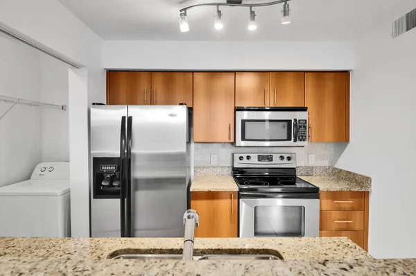 a kitchen with stainless steel appliances kitchen island granite countertop a refrigerator and a stove top oven