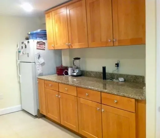 a kitchen with stainless steel appliances granite countertop white cabinets sink and a refrigerator