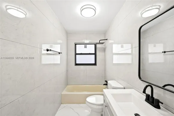 a bathroom with a toilet sink vanity tub and mirror