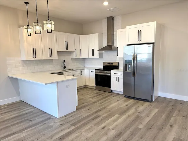 a kitchen with stainless steel appliances granite countertop a sink a stove a refrigerator and island with wooden floor