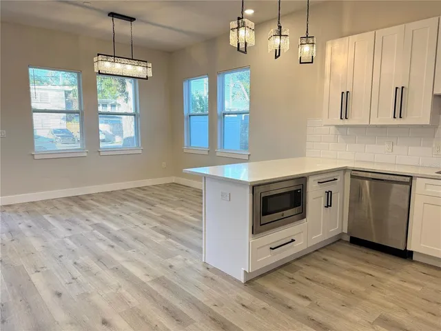a kitchen with stainless steel appliances granite countertop a stove a sink and white cabinets with wooden floor