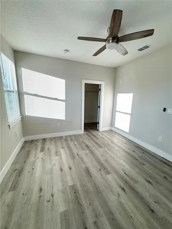 a view of empty room with wooden floor and fan