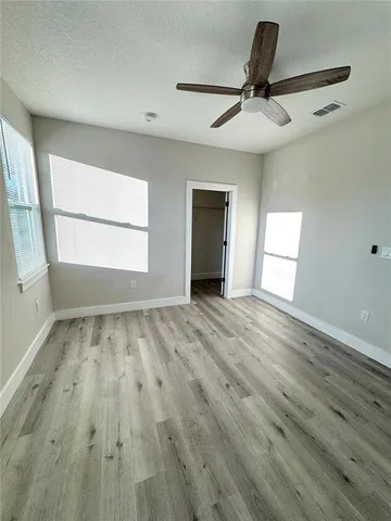 a view of empty room with wooden floor and fan