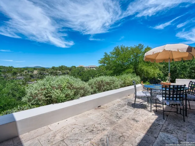 an aerial view of a residential houses with outdoor space and trees all around