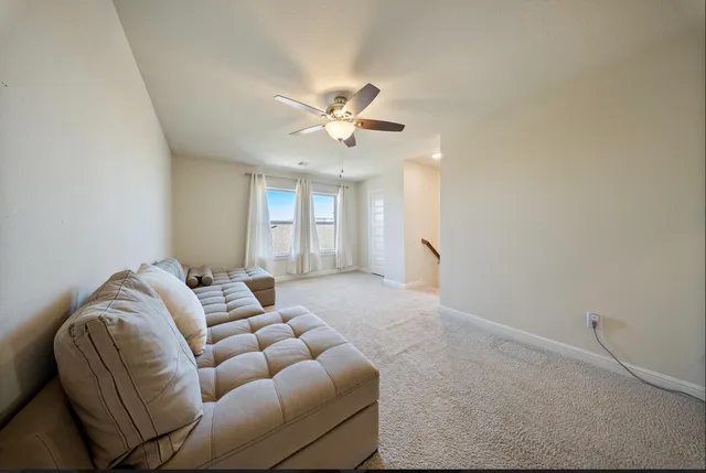 a living room with furniture and a ceiling fan