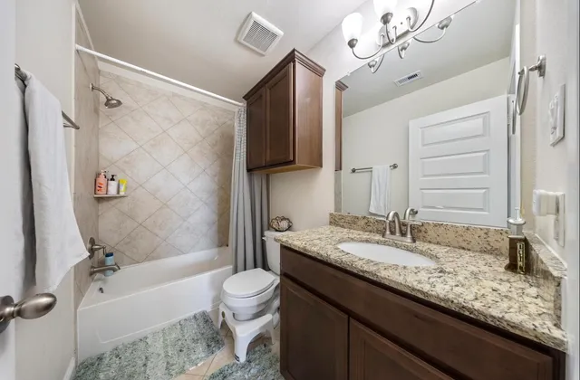 a bathroom with a granite countertop sink a toilet a mirror a bathtub and shower