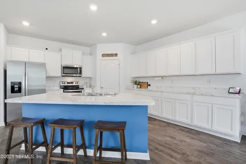 a kitchen with granite countertop a sink white cabinets and stainless steel appliances