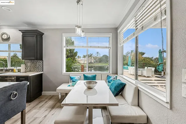 a kitchen with stainless steel appliances a dining table chairs stove refrigerator and cabinets