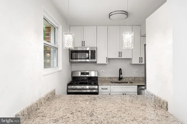 a kitchen with stainless steel appliances granite countertop a sink a stove and a microwave