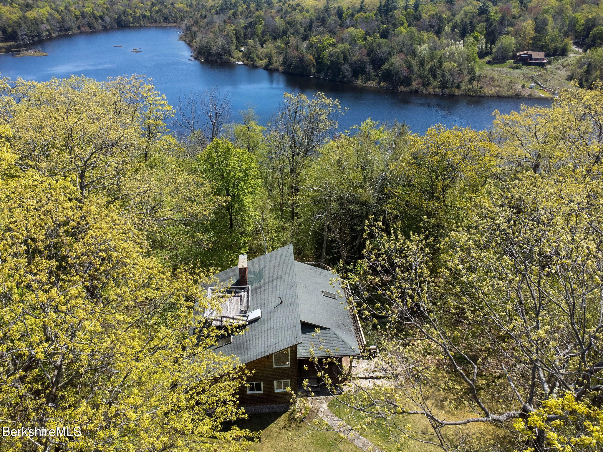 an aerial view of a house with a yard lake and trees all around