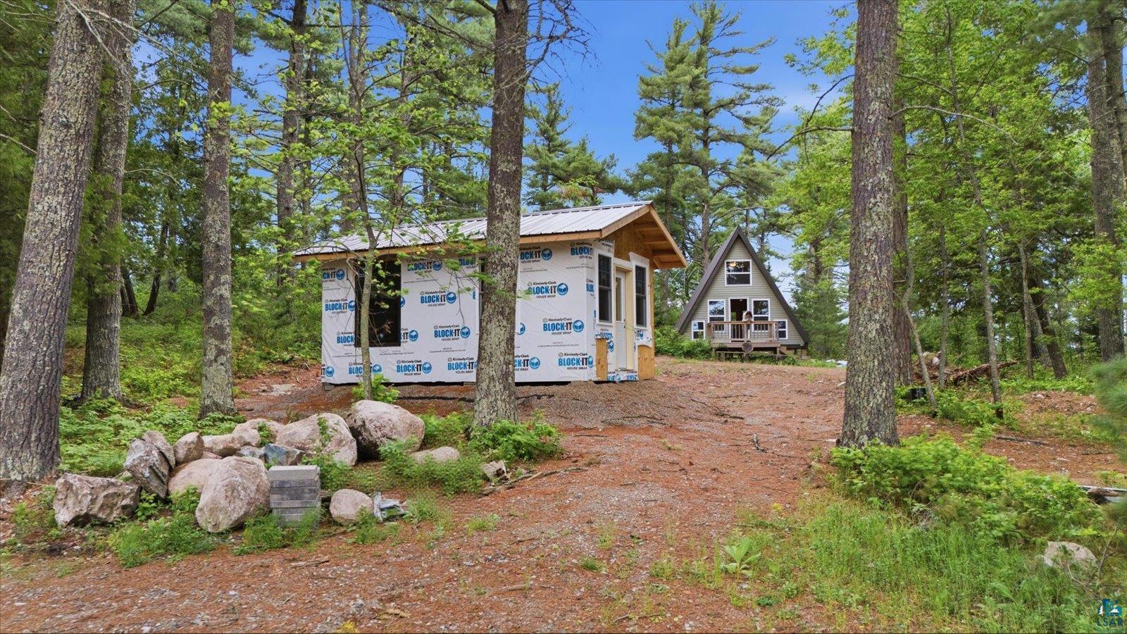 5298 Long Island Tower, MN 55790 - Photo 23 of 31 Wooded lot featuring two distinct structures: an A-frame dwelling with a porch and a smaller, unfinished building
