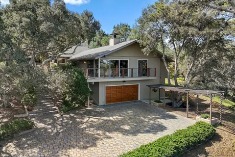 a front view of a house with a garden and trees