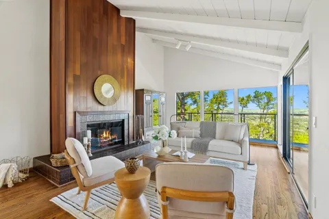 a living room with furniture a fireplace and a floor to ceiling window