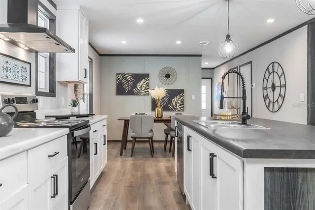 a very nice looking kitchen with granite countertop a stove a sink a dining table and chairs