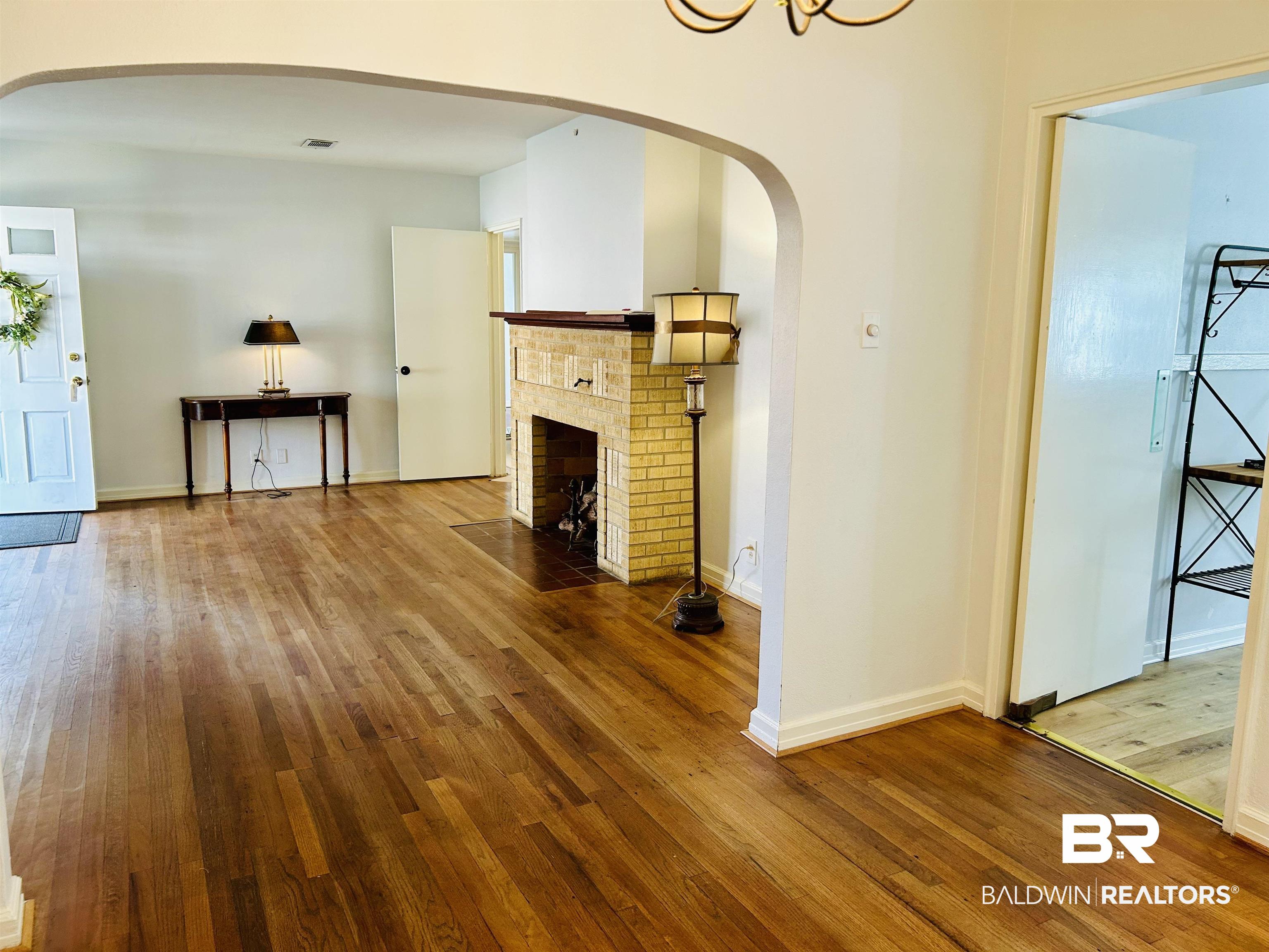 94 Diamond Street Mobile, AL 36611 - Photo 8 of 30 Unfurnished living room featuring hardwood / wood-style floors and a brick fireplace