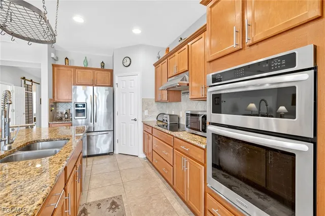 a kitchen with stainless steel appliances granite countertop a table chairs and a refrigerator