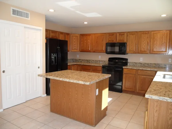 a kitchen with stainless steel appliances granite countertop a stove top oven a sink and a refrigerator