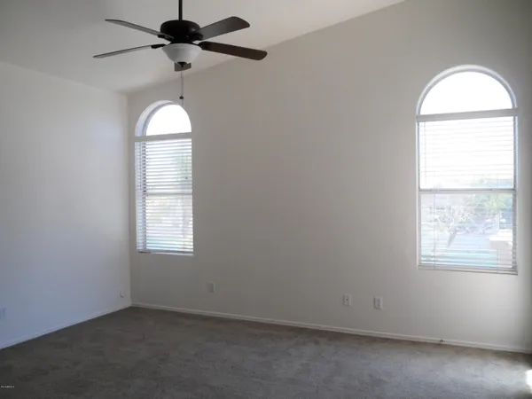 an empty room with windows and fan