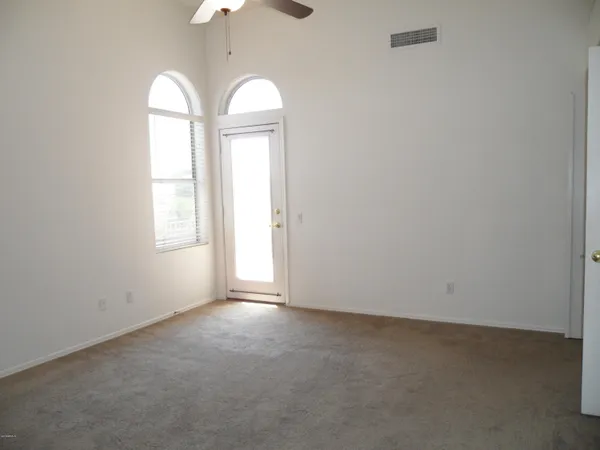 an empty room with chandelier fan and windows