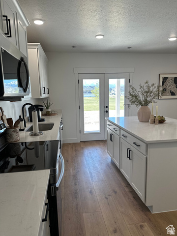 7927 Bristlecone Road, Unit 204 Eagle Mountain, UT 84005 - Photo 14 of 19 Kitchen with white cabinetry, light stone countertops, stainless steel microwave, a textured ceiling, and black range with electric stovetop