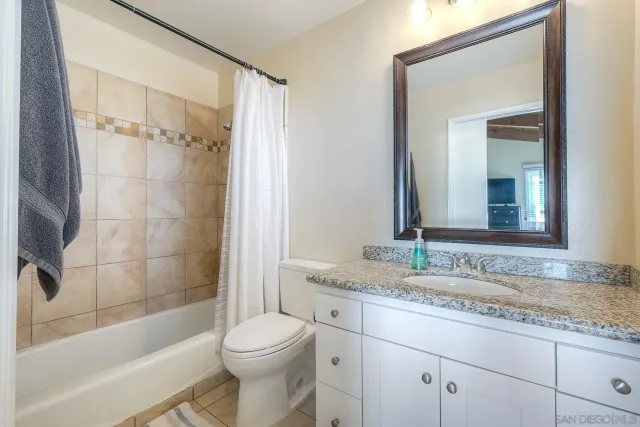 a bathroom with a granite countertop toilet sink and mirror with bathtub