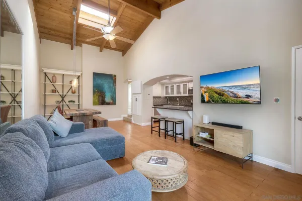 a living room with furniture a flat screen tv and kitchen view