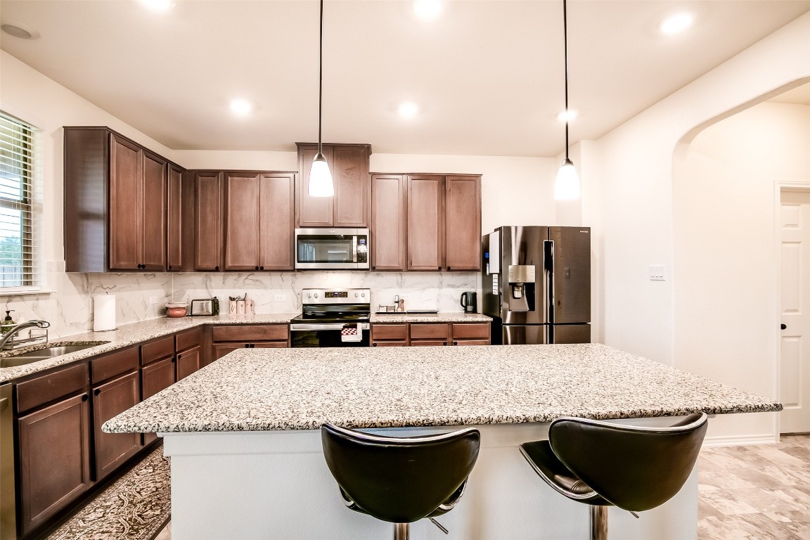 1924 Stringer Pass Leander, TX 78641 - Photo 14 of 34 a kitchen with stainless steel appliances granite countertop a sink stove and cabinets