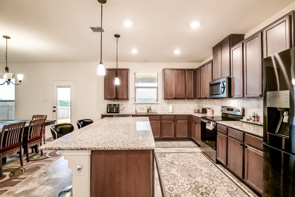 1924 Stringer Pass Leander, TX 78641 - Photo 15 of 34 a kitchen with stainless steel appliances granite countertop a sink stove and refrigerator