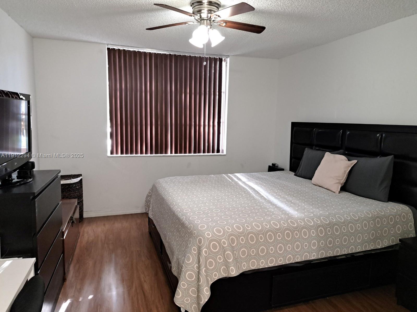 12136 St.Andrews Place, Unit 205 Miramar, FL 33025 - Photo 8 of 23 a bedroom with a bed and wooden floor