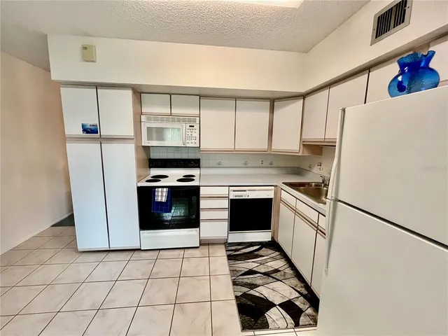 a kitchen with granite countertop a refrigerator and a stove top oven