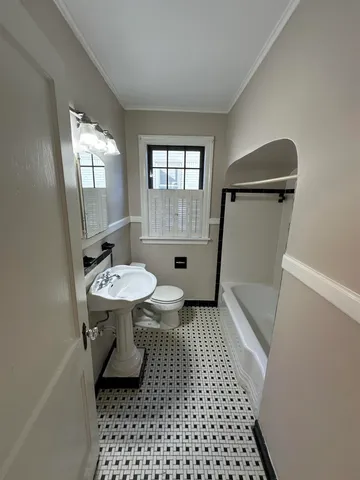 a bathroom with a sink a toilet a window and vanity