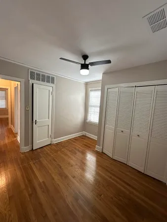 a view of empty room with wooden floor and fan