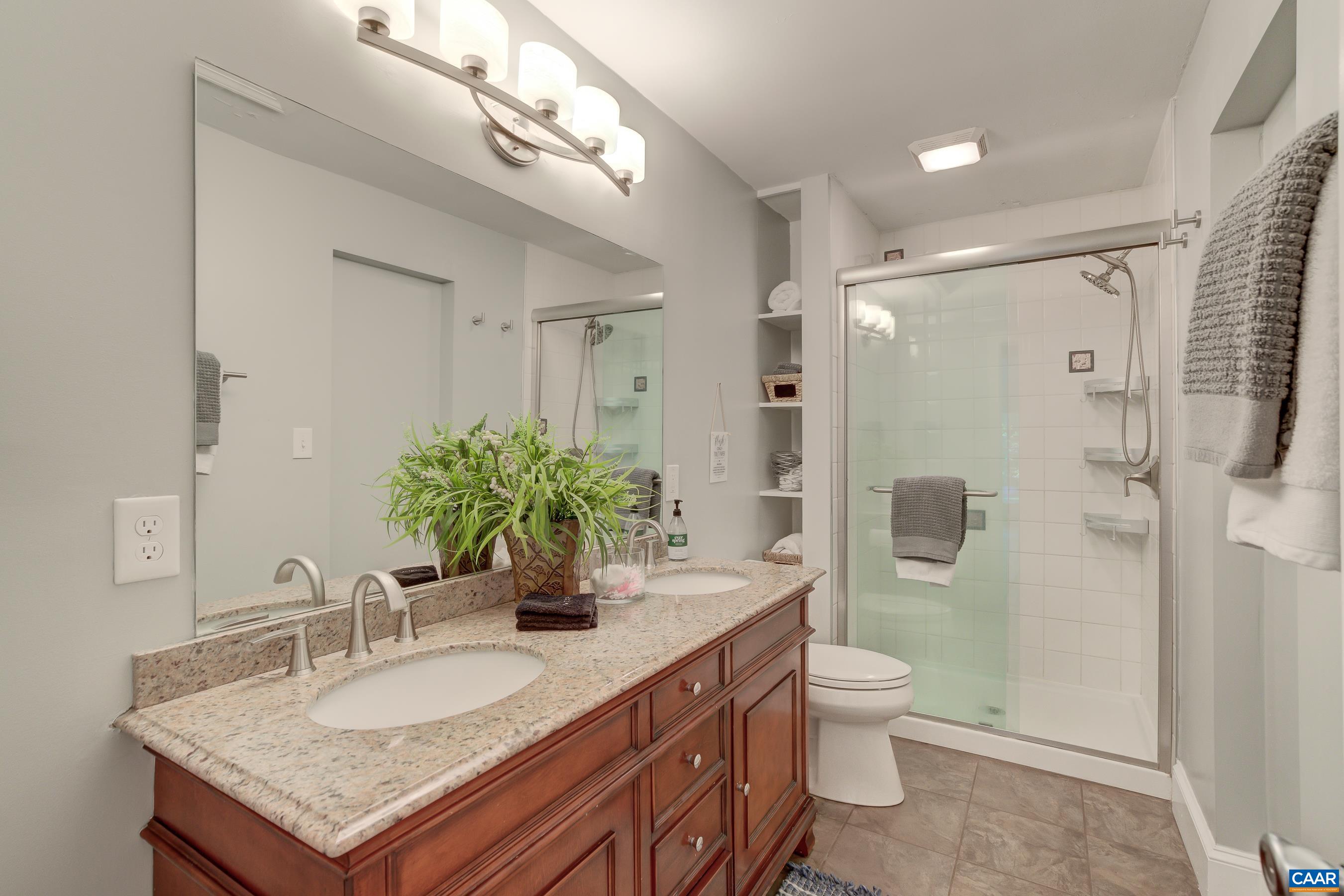 2974 Milton Road Charlottesville, VA 22902 - Photo 22 of 50 a bathroom with a granite countertop sink a toilet a mirror and shower