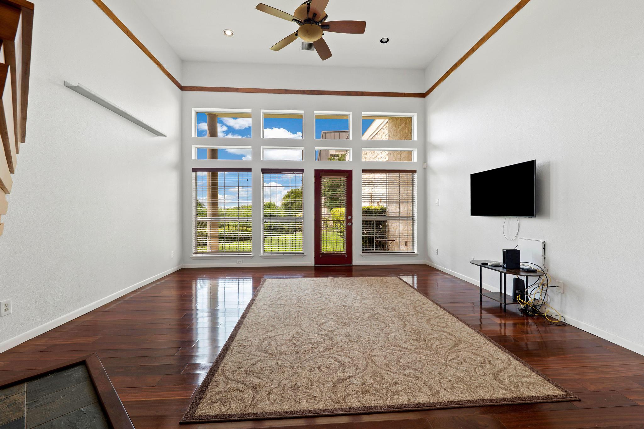 2918 Ranch Road 620, Unit J162 Austin, TX 78734 - Photo 11 of 26 Living space featuring high ceilings, wood-finish flooring, a ceiling fan, fireplace, abundant windows and a door to an outside patio