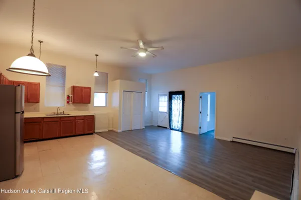 a large room with wooden floor windows and a kitchen