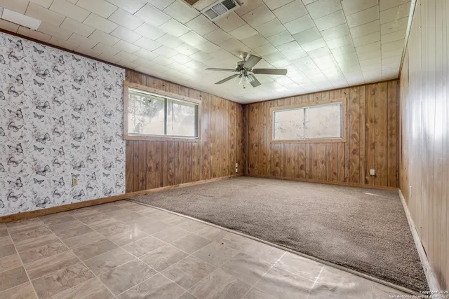 en empty room with windows and ceiling fan