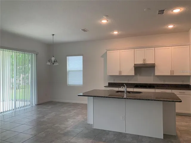 a kitchen with kitchen island granite countertop a sink and a stove top oven