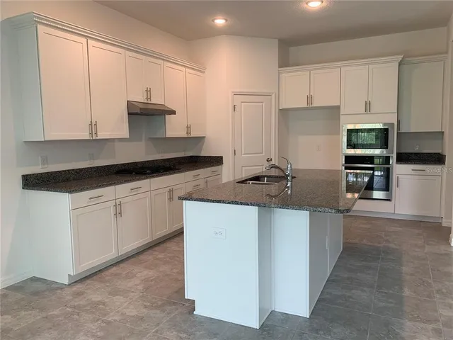 a kitchen with granite countertop a sink stove and refrigerator