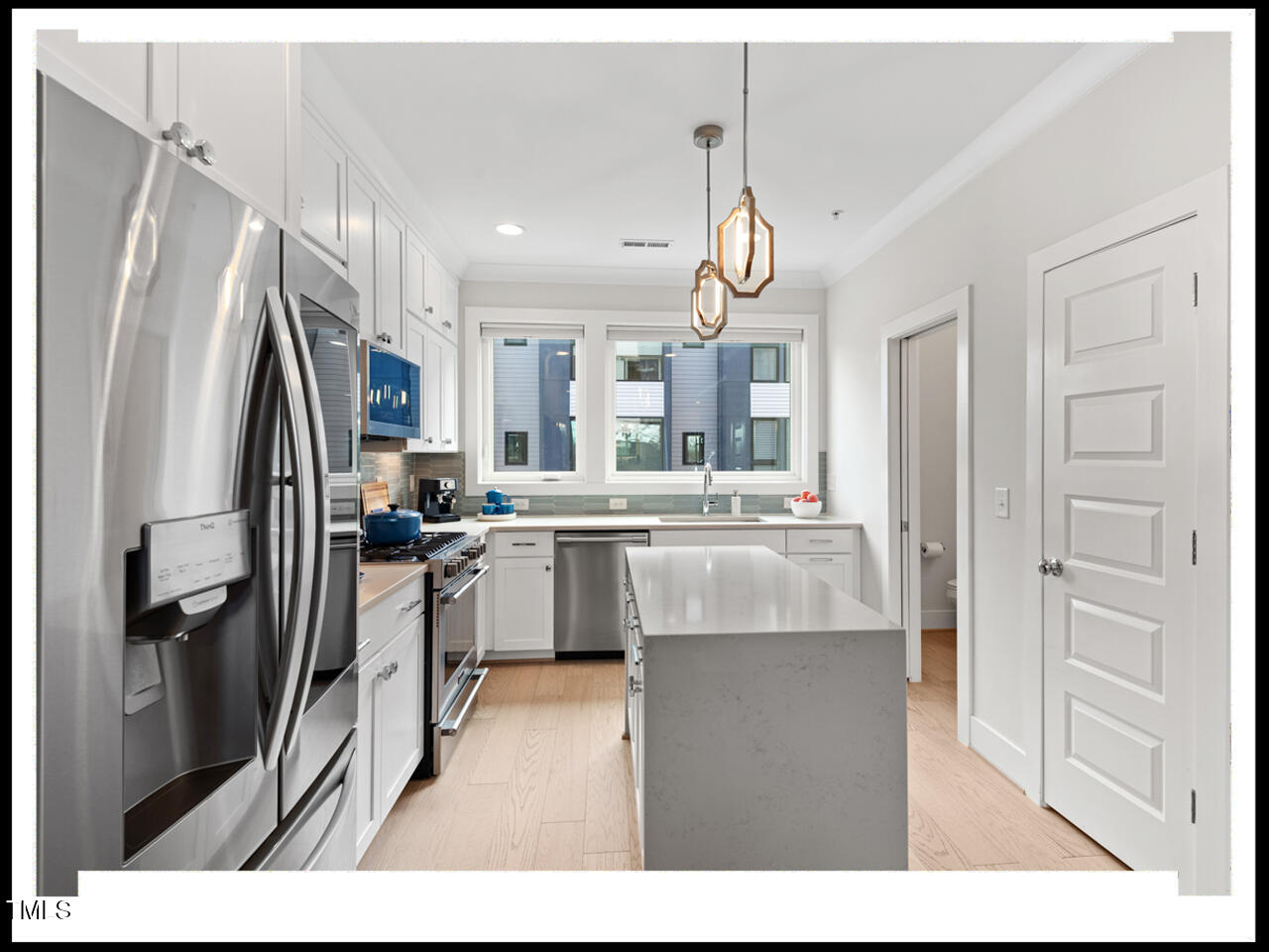 712 East Edenton Street, Unit 105 Raleigh, NC 27601 - Photo 17 of 48 a kitchen with kitchen island a counter top space a refrigerator a sink and cabinets