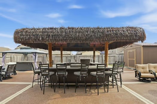 24714 Longwood Forest Drive Spring, TX 77373 - Photo 18 of 21 This outdoor space features a charming tiki bar with a thatched roof and ample seating. It's perfect for entertaining and enjoying sunny days.