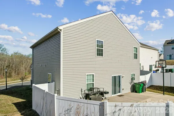 a view of a white house with a small yard and wooden fence