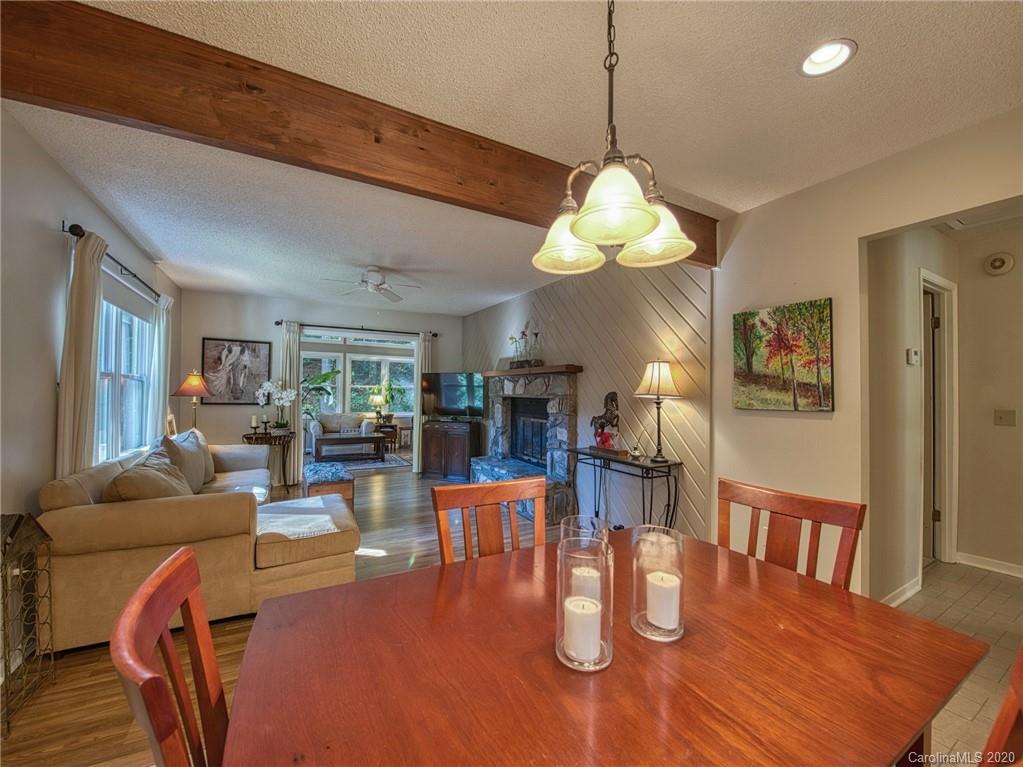 311 Riddle Cove Road Maggie Valley, NC 28751 - Photo 14 of 35 a dining room with wooden floor a chandelier a wooden table and chairs