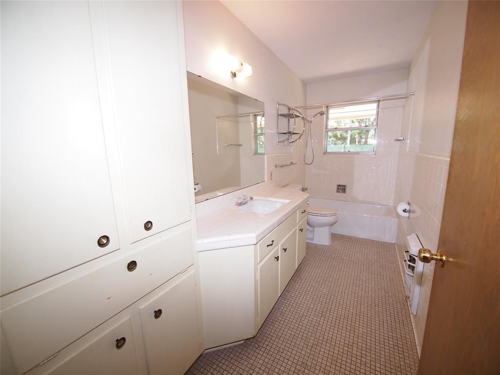 1441 Brazos Street Graham, TX 76450 - Photo 14 of 34 a bathroom with a sink a toilet and shower